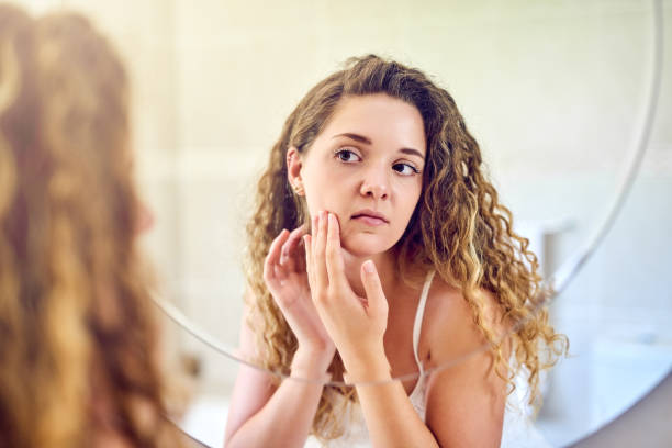 Shot of a young woman squeezing a pimple on her face in the bathroom at home