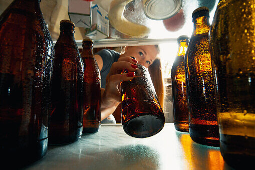 A girl keeping beer bottle in fridge