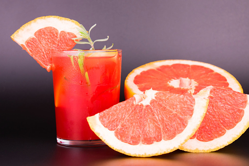 A glass of cold grapefruit juice on a black background. Close-up.