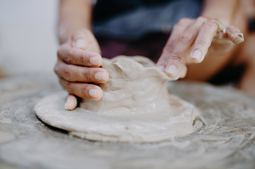 Hands making pottery on a potters wheel