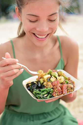 Woman eating local Hawaii food dish Poke bowl salad