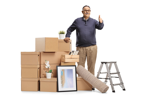 Mature man standing next to a pile of cardboard boxes packed