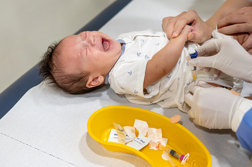 Newborn baby boy crying and screaming while taking vaccine