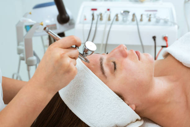 Cosmetologist doing oxygen infusion care of face of beautiful woman