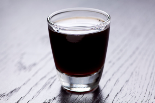 Dark colored alcohol shot inside a shot glass