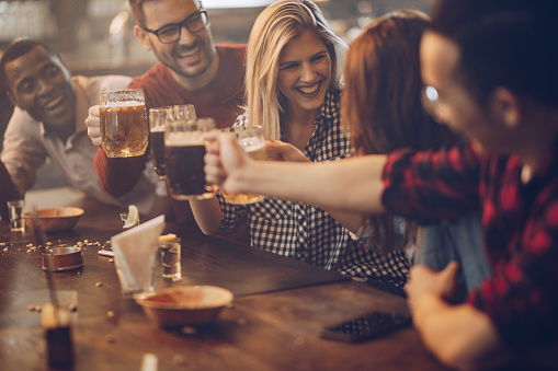 Cheerful friends toasting with beer and having fun in a bar