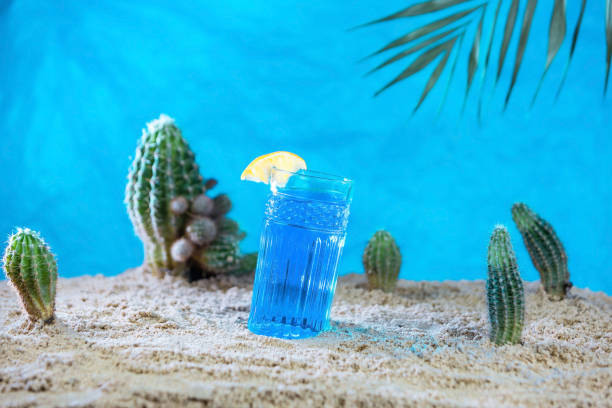 a glass of blue Thai tea on the sand with cacti. soft drinks in the heat